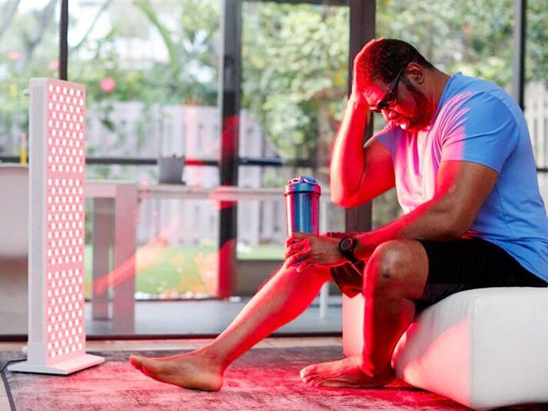 Athlete using red light therapy panel in gym recovery room